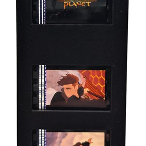 May include: Black film cell display featuring three frames from the animated movie "Treasure Planet." The top frame displays the movie title. The other frames show animated characters in action. The display is black.