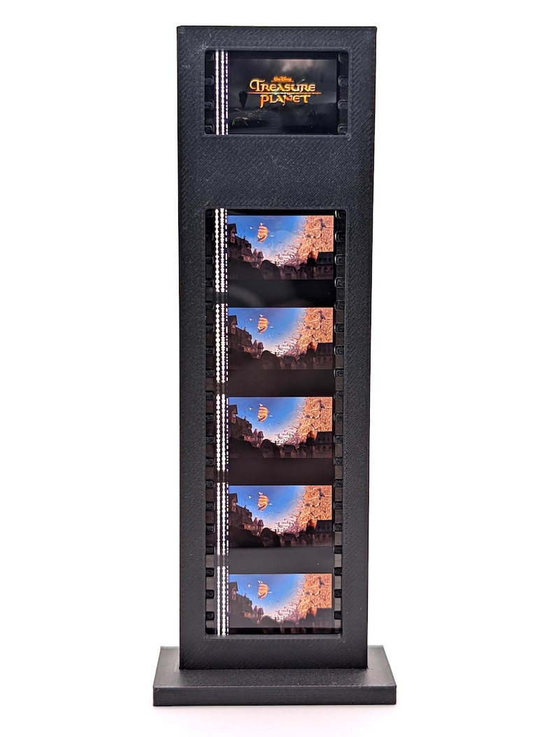 May include: A black film strip display featuring scenes from the movie "Treasure Planet." The display includes the movie title at the top and several film cells showing a ship sailing across a blue sky. The display is rectangular and stands upright.