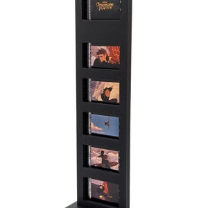 May include: A black film strip display stand featuring five film cells with scenes from "Treasure Planet." The top cell displays the movie title. The stand is rectangular with a base for stability.