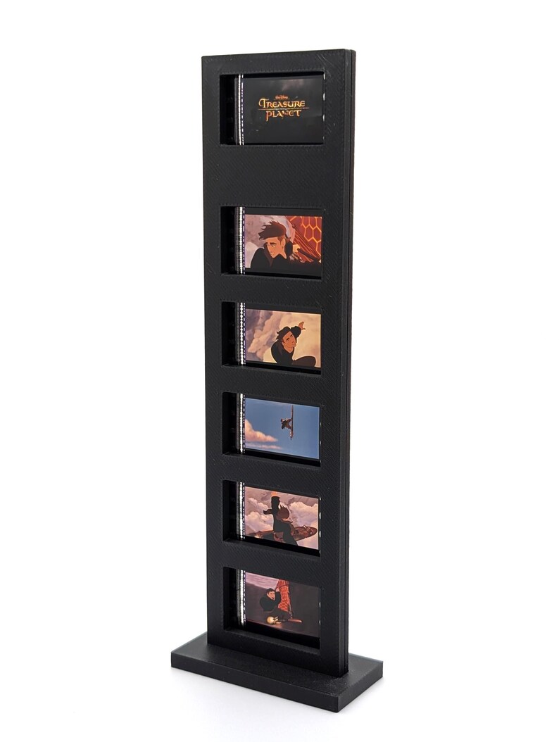 May include: A black film strip display stand featuring five film cells with scenes from "Treasure Planet." The top cell displays the movie title. The stand is rectangular with a base for stability.