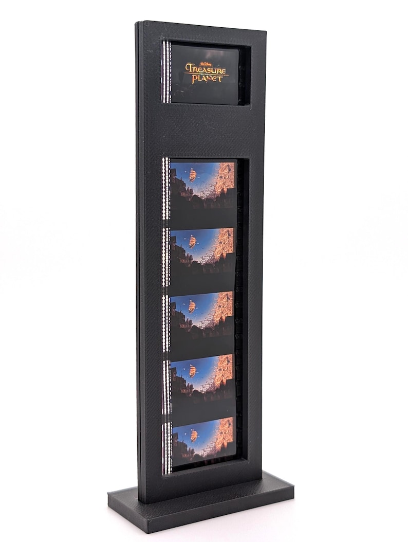 May include: Black display stand featuring film strips with images from "Treasure Planet." The stand has a rectangular frame with a base. The top section displays the movie title. The film strips show a ship sailing in a blue sky.