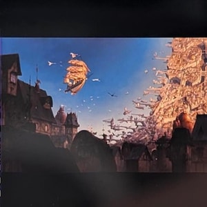 May include: A film strip showing a fantastical scene with a sailing ship floating in the sky above a town. The sky is blue with birds flying. Buildings and structures are on the left and right sides of the image.
