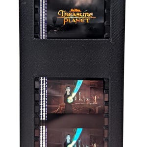 Puede incluir: Marco rectangular negro con el logotipo de Disney Treasure Planet e im&aacute;genes de tiras de pel&iacute;cula. La tira de pel&iacute;cula muestra escenas de la pel&iacute;cula, incluido un personaje que sostiene un objeto azul brillante.