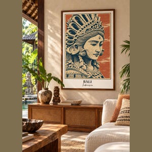 Può includere: Una stampa artistica da parete rettangolare che presenta un'illustrazione stilizzata di una persona che indossa un copricapo ornato in tonalità blu scuro e crema su uno sfondo color terracotta testurizzato, con il testo BALI Indonesia stampato in basso.