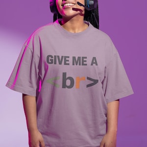May include: A person wearing a lilac-colored t-shirt with the text "GIVE ME A <br>". The letters "br" are in orange and green. The person is wearing a headset and black shorts.