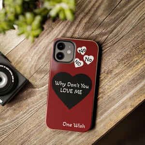 Könnte beinhalten: Eine dunkelrote Smartphone-Hülle mit einem großen schwarzen Herz, das in der Mitte den weißen Text "Why Don't You LOVE ME" trägt. Über dem Herz befinden sich drei kleine weiße Herzen mit dem Text "No" darin und "One Wish" am unteren Rand.