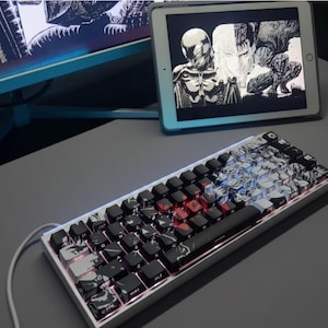 May include: A white and black mechanical keyboard with custom keycaps. The keycaps feature a black and white graphic design. The keyboard has red and blue LED backlighting. A tablet displaying a black and white image is in the background.