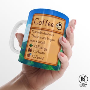 Może przedstawiać: Biały ceramiczny kubek do kawy z owiniętym wzorem. Wz&oacute;r zawiera słowo "Coffee" w pikselowym tekście, wraz z tekstem "It smells delicious. This is sure to give you a boost." oraz statystykami energii, zdrowia i prędkości.