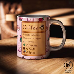 Może przedstawiać: R&oacute;żowy kubek do kawy z białym uchwytem, ​​z pikselową grafiką jedzenia i napisem "Coffee". Kubek zawiera tekst "It smells delicious. This is sure to give you a boost."