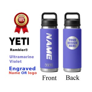 May include: Two Ultramarine Violet YETI Rambler bottles. One bottle has the name "NAME" in white, the other has a silver circle with "YOUR DESIGN HERE". The bottles have black handles and silver bases. The text "Engraved Name OR logo" is also visible.