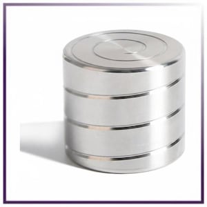 May include: A cylindrical metal fidget spinner with a polished silver finish. The top surface features a subtle engraved spiral pattern, while the side of the cylinder is divided into four distinct horizontal sections by thin, recessed grooves.