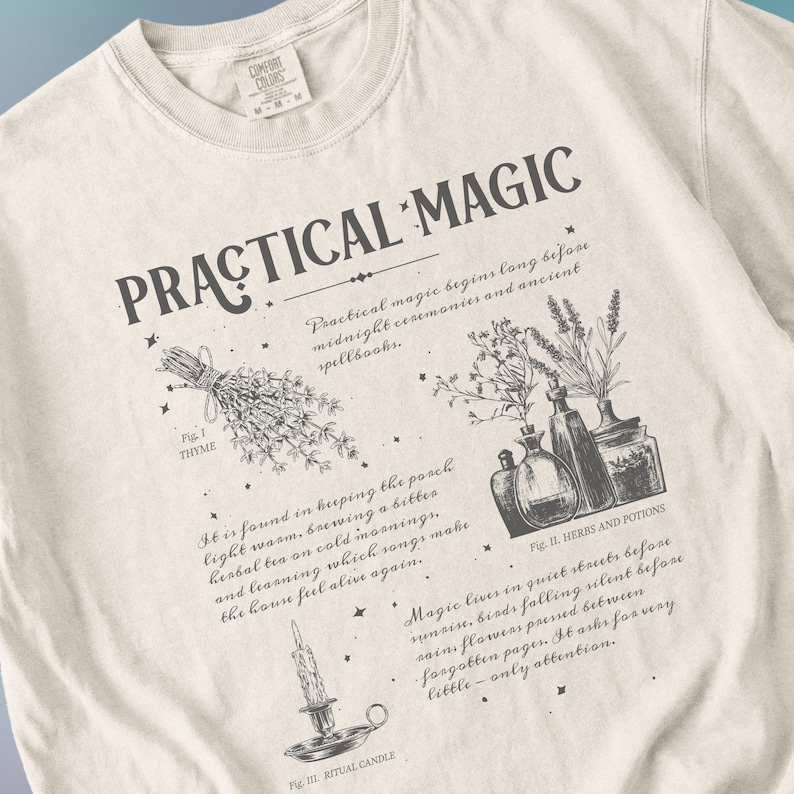 May include: Cream-colored sweatshirt with the words "PRACTICAL MAGIC" in dark gray. The design includes illustrations of thyme, herbs and potions, and a ritual candle. Text describes practical magic and its origins.