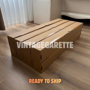 May include: A stack of rectangular brown cardboard shipping boxes arranged in a grid. The text VINTAGEGARETTE is printed in white across the centre of the boxes, and the text READY TO SHIP is printed in orange at the bottom of the image.