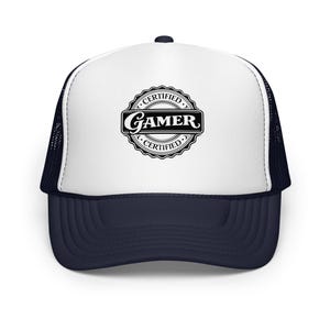 Puede incluir: Gorra de camionero azul marino y blanca con visera curva. El panel frontal muestra un emblema circular en blanco y negro que dice "CERTIFIED GAMER" en una fuente estilizada.