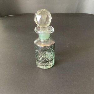 Puede incluir: Un decantador de vidrio transparente con cuerpo cilíndrico, un patrón de corte de diamante y un cuello liso. El decantador está rematado con un tapón de vidrio esférico y facetado que encaja de forma segura en la abertura.