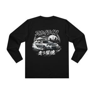 May include: Black long-sleeved shirt with a graphic of a silver sports car drifting. The design includes Japanese text, a mountain, and a city skyline. The shirt is made of a soft material, suitable for casual wear.