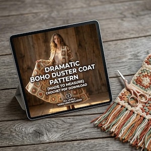 Może przedstawiać: Tablet wyświetla wzór na szydełkowy płaszcz boho. Na ekranie widnieje kobieta w płaszczu. Tekst na ekranie brzmi "DRAMATIC BOHO DUSTER COAT PATTERN (MADE TO MEASURE) CROCHET PDF DOWNLOAD." Nożyczki i szydełkowy szal leżą na drewnianej powierzchni.