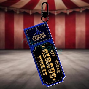 Puede incluir: Llavero de boleto Freak Circus negro y azul con letras doradas. El boleto tiene un patr&oacute;n de diamantes y un gr&aacute;fico de carpa de circo. El llavero tiene un cierre de metal negro.