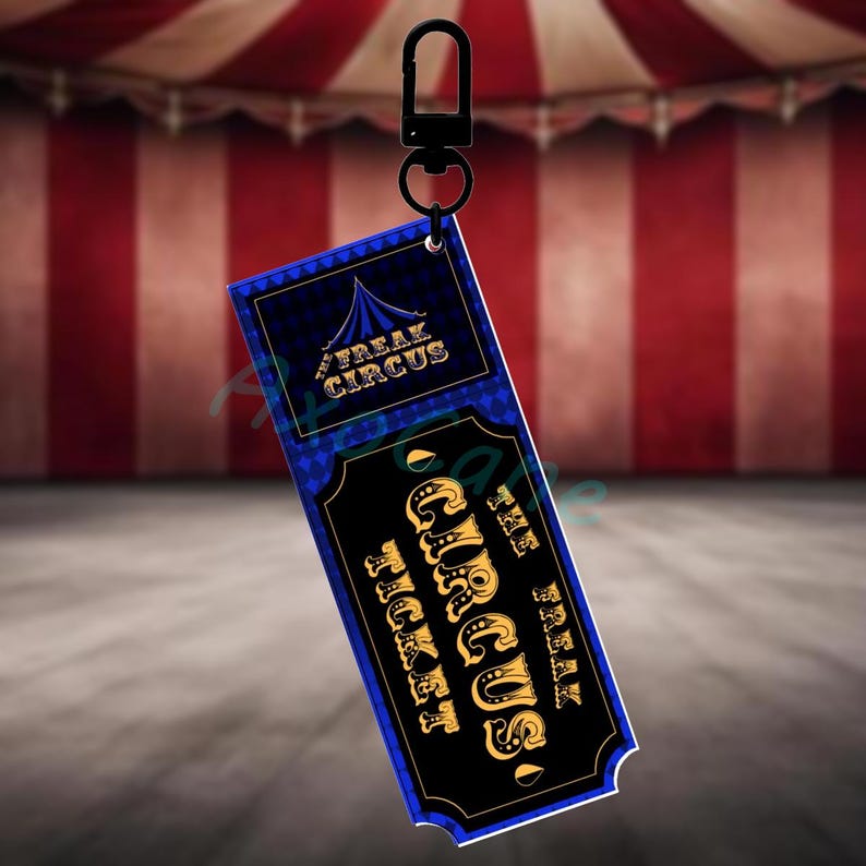Puede incluir: Llavero de boleto Freak Circus negro y azul con letras doradas. El boleto tiene un patr&oacute;n de diamantes y un gr&aacute;fico de carpa de circo. El llavero tiene un cierre de metal negro.
