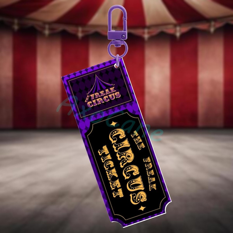 Puede incluir: Un llavero de boleto de Freak Circus morado y negro con letras doradas y un cierre morado. El boleto presenta el texto "Freak Circus Ticket" y un gr&aacute;fico de carpa de circo. El fondo es una carpa de circo a rayas rojas y blancas.