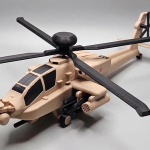 May include: Tan and black toy helicopter with four rotor blades and a tail rotor. The model has detailed features, including a cockpit, weapons, and landing gear. The helicopter is a miniature replica of a military aircraft.