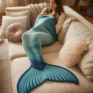 Puede incluir: Una manta con forma de cola de sirena azul y turquesa. La manta está hecha de un material suave y tejido, con un patrón de escamas en el cuerpo y un diseño acanalado en la cola. Mide aproximadamente 152 cm de largo.