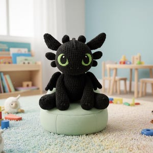 Peut inclure: Une peluche de dragon noir au crochet avec de grands yeux verts et de petites ailes. Le dragon est assis sur un pouf vert clair dans une salle de jeux pour enfants. La pièce a un mur bleu clair et un tapis coloré.