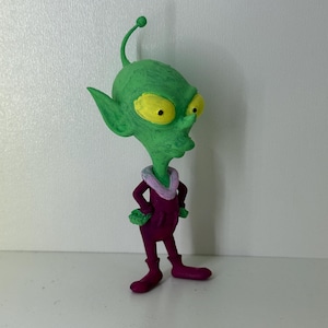 May include: A white ceramic mug with a black handle and the text "But First, Coffee" in a bold, black font. The mug is sitting on a wooden surface. The mug is 10 cm tall.