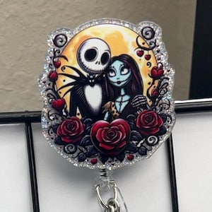 May include: A badge reel featuring Jack Skellington and Sally from The Nightmare Before Christmas, set against a yellow moon. The design includes red roses, hearts, and a glittery border. The reel has a silver clip.