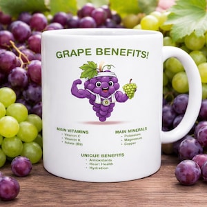 May include: White ceramic mug with the text "GRAPE BENEFITS!" and a cartoon grape character flexing its muscles. The mug lists vitamins, minerals, and unique benefits of grapes. Grapes are in the background.