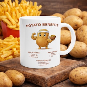 Puede incluir: Taza de cerámica blanca con el texto "POTATO BENEFITS!" y un personaje de dibujos animados de patata flexionando su brazo. La taza también enumera vitaminas, minerales y beneficios únicos de las patatas. Patatas fritas y patatas en el fondo.