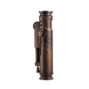 May include: A bronze-colored, vintage-style lighter with a textured surface. The lighter has a cylindrical body with a hinged side panel, a small lever, and a decorative top and bottom. The design features a series of small holes and a circular button.
