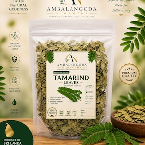 Puede incluir: Una bolsa de plástico transparente llena de hojas de tamarindo secas, con el texto "TAMARIND LEAVES" y "100% NATURAL PRODUCT". La bolsa está sobre una superficie de madera, con un cuenco de madera con hojas y hojas verdes.