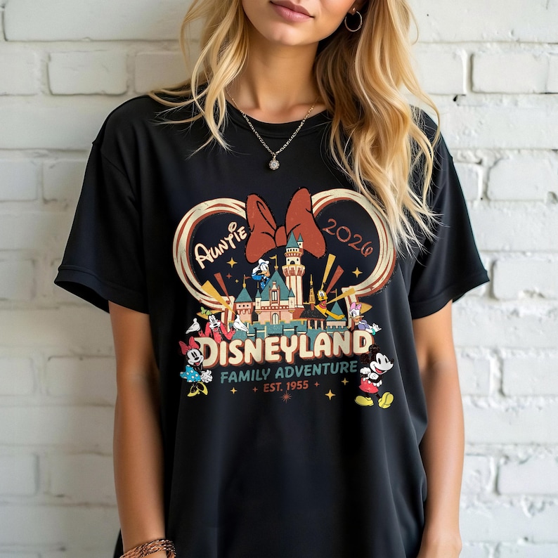 May include: Black t-shirt featuring a Disneyland graphic with Minnie Mouse's bow, the word "Auntie", and the year 2020. The graphic includes a castle, Mickey Mouse, and other characters. The words "Family Adventure" and "Est. 1955" are also included.