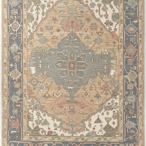 May include: A rectangular area rug with an intricate, symmetrical design. The rug features a central medallion in shades of blue-gray, peach, and beige, surrounded by a border of navy blue and complementary colors. The overall style is traditional.