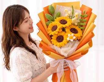 Könnte beinhalten: Ein gehäkelter Sonnenblumenstrauß mit drei großen gelben Sonnenblumen mit dunkelbraunen Mitten, einer kleinen weißen Blume und grünen gehäkelten Blättern. Der Strauß ist in geschichtetes orangefarbenes und gelbes Papier mit einer weißen Schleife gewickelt.
