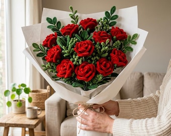 Könnte beinhalten: Ein Blumenstrauß aus leuchtend roten Filzrosen mit tiefroten Blütenblättern und strukturierten grünen Blättern. Die Blumen sind zu einem Bündel arrangiert, in weißes Papier eingewickelt und an der Basis mit einer einfachen braunen Kordel gebunden.