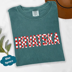 Może przedstawiać: Niebiesko-zielona koszulka z napisem "HRVATSKA" w czerwono-białą kratę. Koszulka marki Comfort Colors. Brązowy kapelusz widoczny w prawym g&oacute;rnym rogu. Niebieski dymek z napisem "Blue Spruce" znajduje się w lewym dolnym rogu.