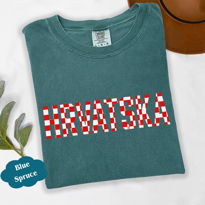 Może przedstawiać: Niebiesko-zielona koszulka z napisem "HRVATSKA" w czerwono-białą kratę. Koszulka marki Comfort Colors. Brązowy kapelusz widoczny w prawym g&oacute;rnym rogu. Niebieski dymek z napisem "Blue Spruce" znajduje się w lewym dolnym rogu.
