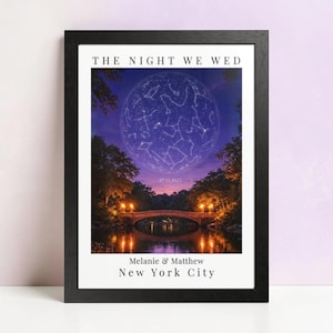 May include: Framed print featuring a night sky with constellations over a park scene. The text "THE NIGHT WE WED" is at the top, with the date "07.13.2023" and names "Melanie & Matthew" and "New York City" at the bottom. The frame is black.