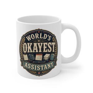 May include: A white ceramic mug featuring a circular graphic with the text "WORLD'S OKAYEST ASSISTANT". The design includes illustrations of a clipboard, telephone, calendar, pen, and document tray, all framed by a decorative laurel wreath border.