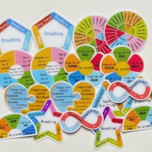 Może przedstawiać: Kolekcja kolorowych naszywek z tkaniny z tekstem i diagramami związanymi z ćwiczeniami oddechowymi i uważnością. Kształty obejmują koła, kwiaty i gwiazdy. Naszywki zawierają frazy takie jak "Wdech", "Wydech" i "Rzeczy, które mogę kontrolować."