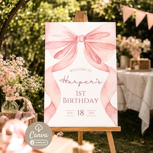 Può includere: Un cartello rettangolare bianco su un cavalletto di legno con un grande fiocco rosa ad acquerello nella parte superiore. Il testo recita: Welcome to Harper's 1st Birthday, Jun 18, 2pm. Il design include nastri rosa che incorniciano il testo.