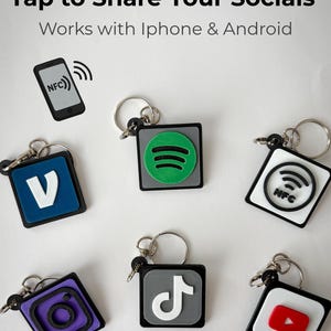 May include: Keychains with social media logos, including Spotify, Instagram, TikTok, and YouTube. Each keychain has a square design with a metal ring and key. The text "Tap to Share Your Socials" and "Works with iPhone & Android" are visible.