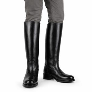 May include: A pair of knee-high black boots with a smooth finish, rounded toes, and a low block heel. The boots feature a structured shaft that reaches just below the knee, with visible stitching details around the ankle and heel area.