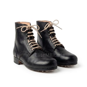 May include: A pair of black leather ankle boots with beige laces. The boots have a classic design with a rounded toe and a low heel. The boots are displayed on a white background.