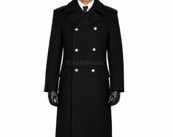 May include: A black double-breasted wool overcoat featuring a wide collar, six metallic buttons arranged in two vertical rows, two side pockets with flaps, and long sleeves. The coat is worn over a white collared shirt and a black necktie.
