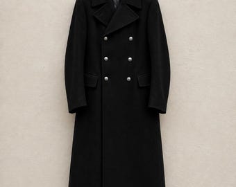 May include: A long, black, double-breasted coat featuring a wide lapel collar, long sleeves, and two rows of six silver-toned metallic buttons. The coat includes two side pockets with flaps and is displayed hanging on a black plastic hanger.