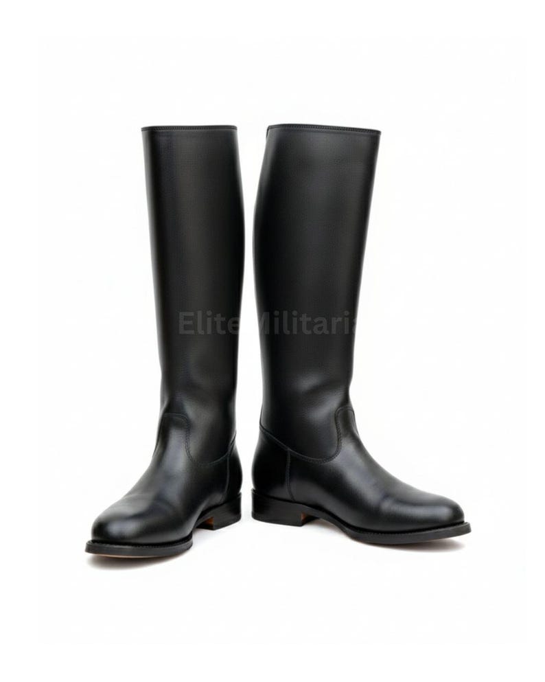 May include: A pair of black leather riding boots. The boots are tall, reaching the knee, with a smooth, polished finish. The soles are flat and the heels are low. The text "Elite Militari" is visible on the image.