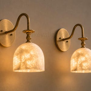 Pair of modern alabaster wall sconces with antique brass finish, handcrafted mid century bathroom vanity wall lights on a warm beige textured wall
Pair of handcrafted alabaster brass wall lights, modern mid century wall sconces for bathroom, bedroom, or entryway
Modern brass wall sconce pair with natural alabaster shades, elegant luxury bathroom vanity lighting fixture
Antique brass alabaster wall light fixture, handmade modern wall sconces with warm illumination for luxury interiors